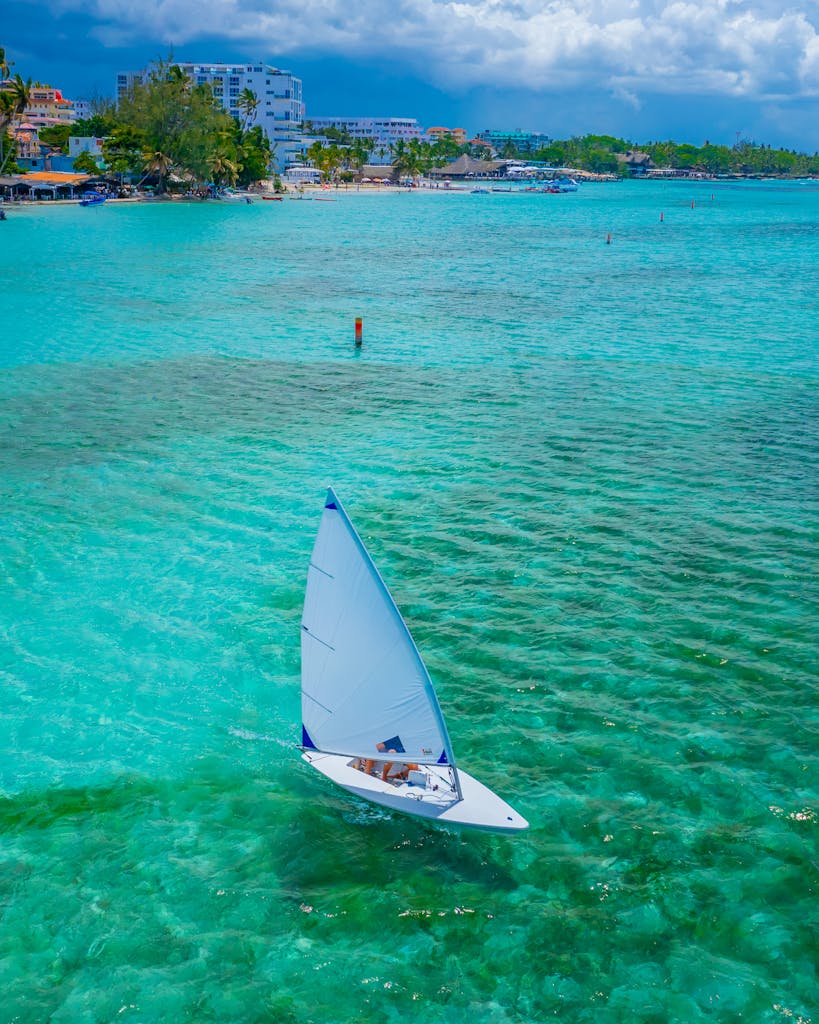 Stunning aerial shot of a sailboat navigating the clear turquoise waters of the Caribbean coast.